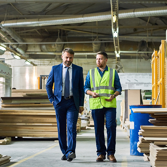 Business man walks with a construction worker through a site