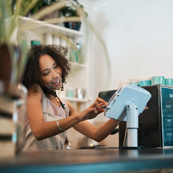 Woman typing on her POS at her coffee shop