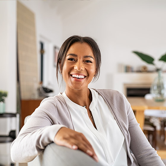 happy young woman sitting on the couch inside her home