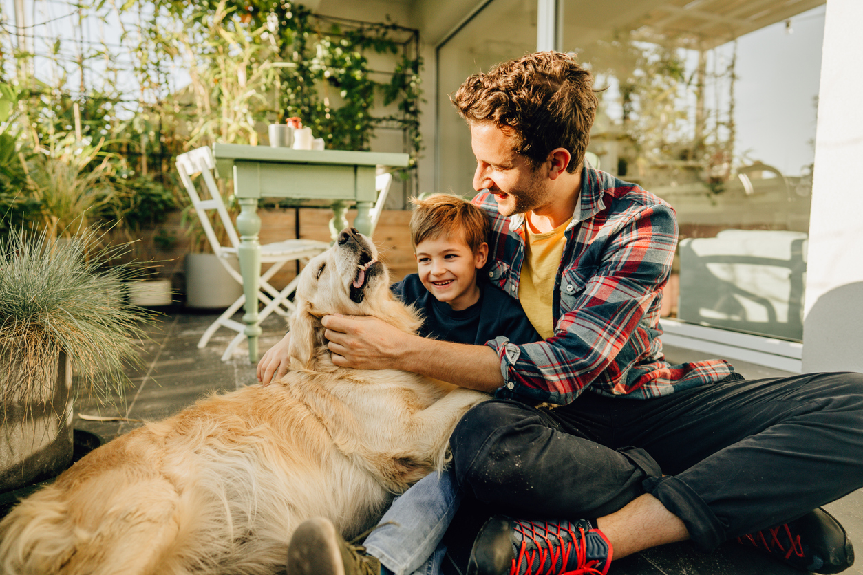 a father and son pet their dog