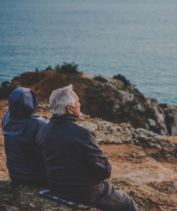 couple sitting on a rocky beach looking out over the ocean