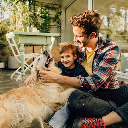 A father and son pet their dog