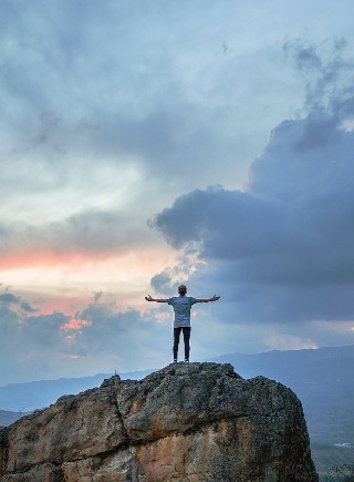 Person on top of a hill with arms wide open
