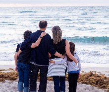 Family posing on a beach overlooking the ocean