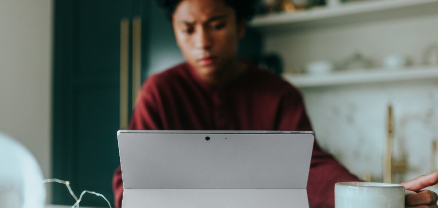 Person sitting with coffee while viewing their tablet