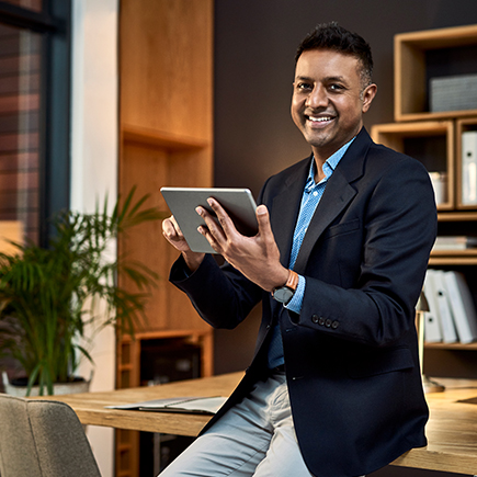 Man sitting on his desk while holding a tablet